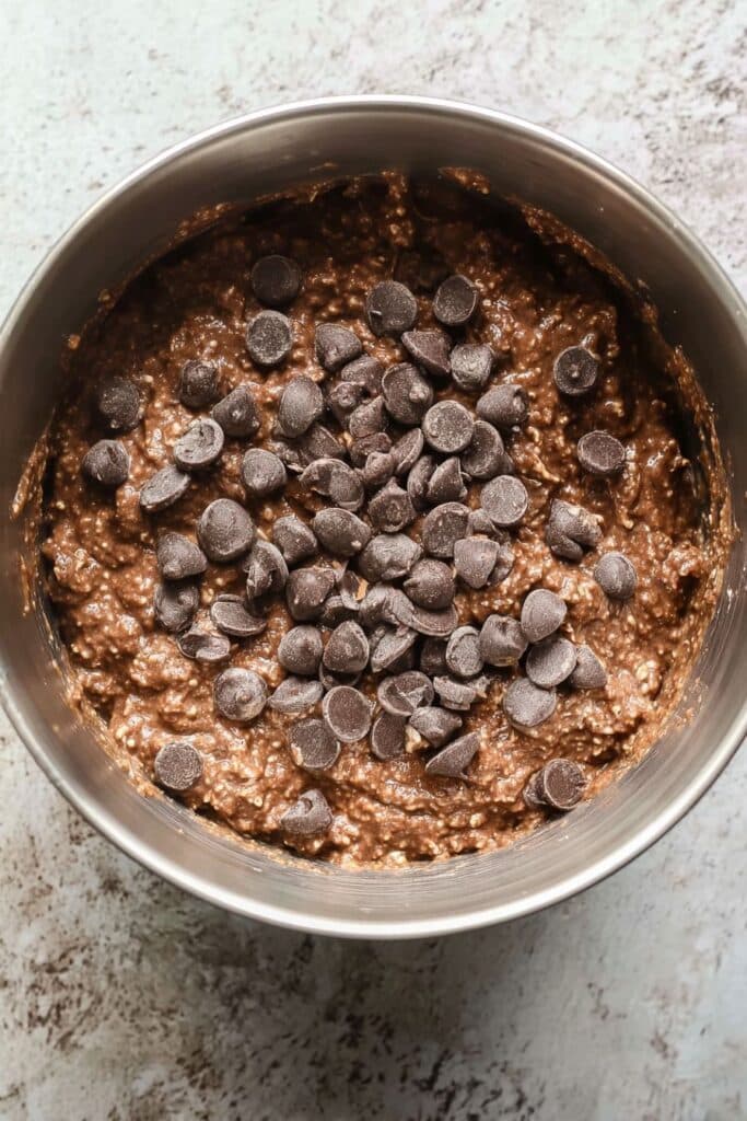 Protein Brownies That Taste Like Fudge and Keep You Full Longer 3 Raw chocolate protein brownie batter topped with dark chocolate chips in a mixing bowl