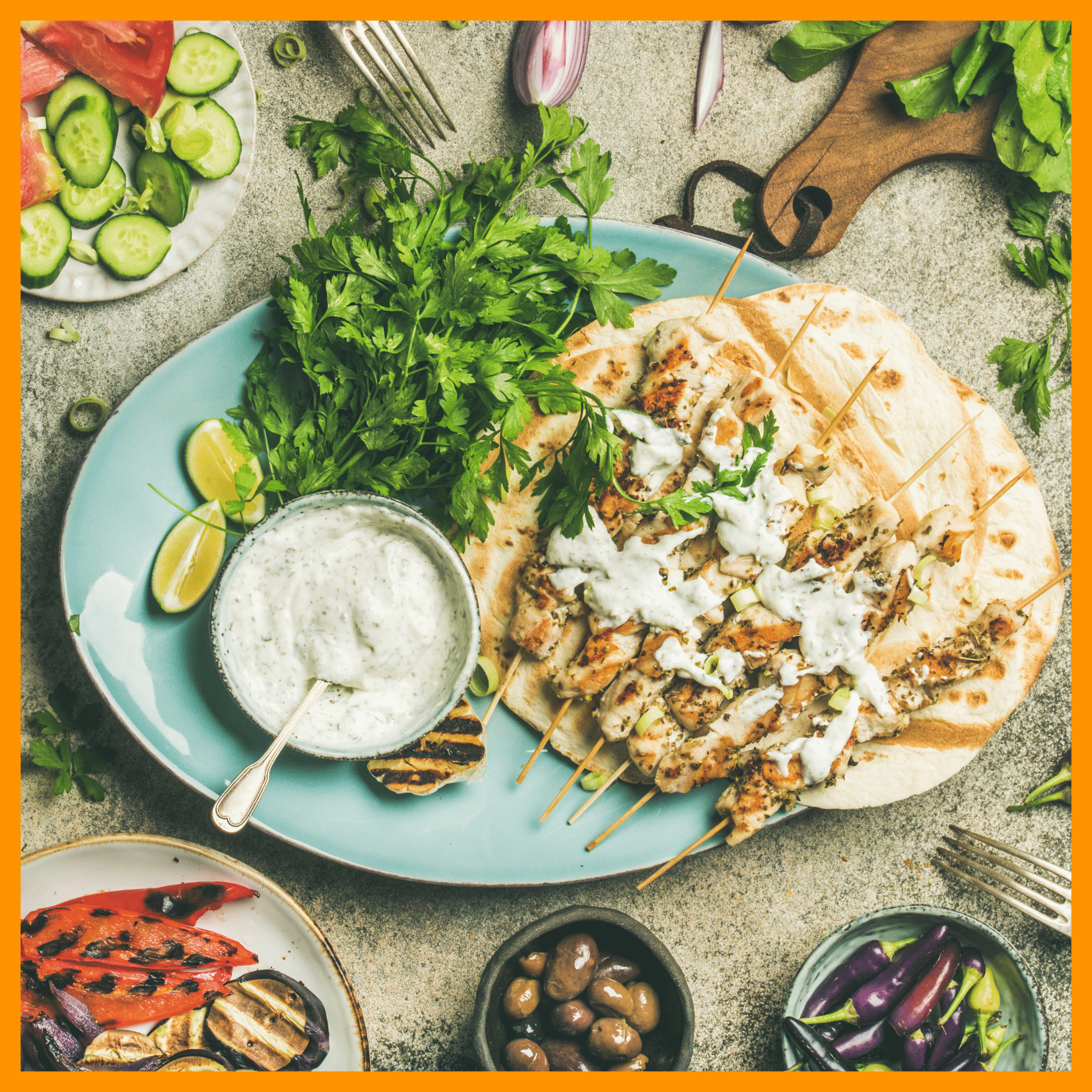 Home 1 Mediterranean chicken skewers with flatbread, tzatziki, olives, grilled vegetables, herbs, and fresh salad on a rustic table.