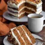 Slice of keto carrot cake with cream cheese frosting and coffee on rustic table