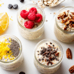 Jars of keto overnight oats topped with raspberries, pecans, lemon zest, chia seeds, and chocolate chips on white background