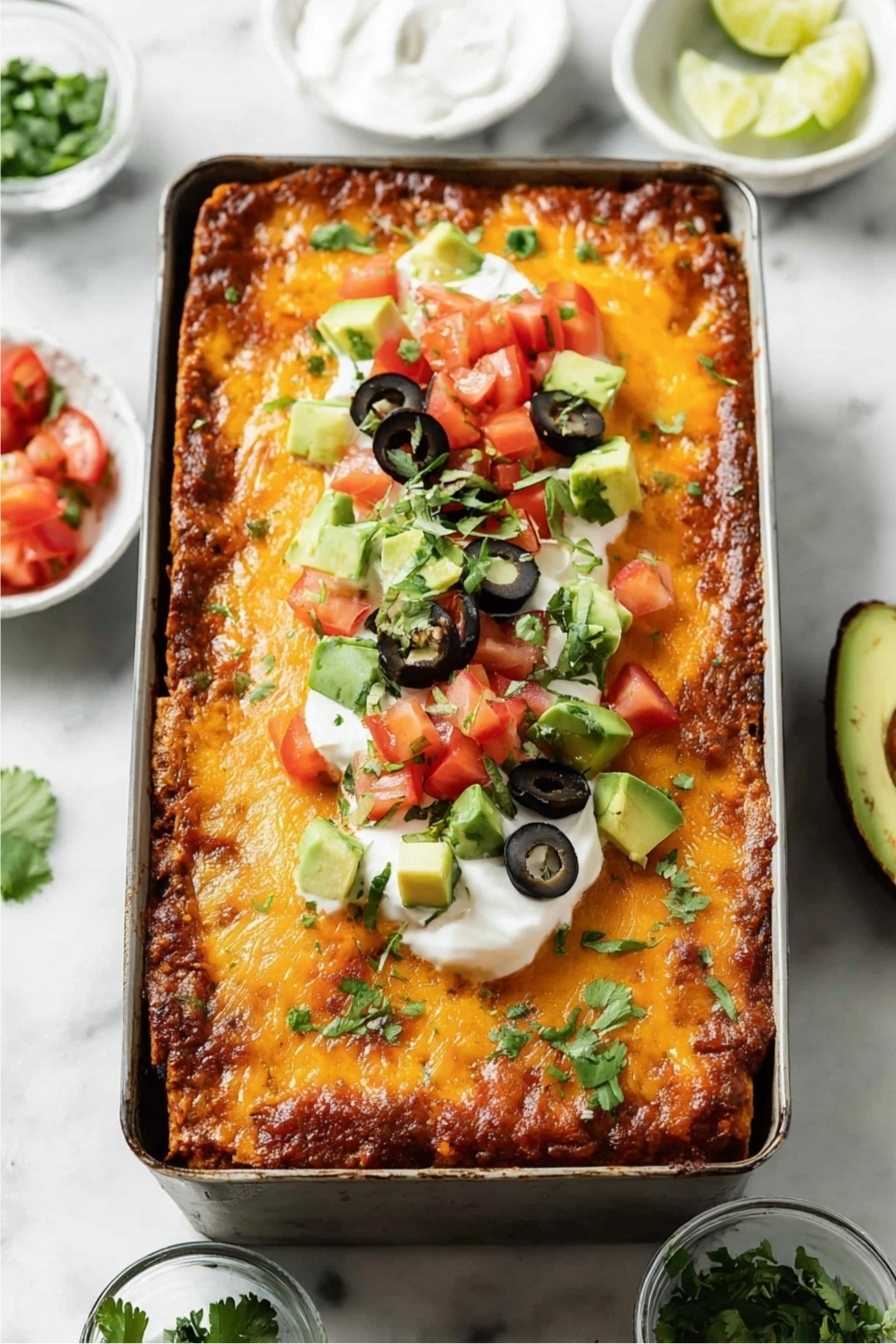 Keto Taco Lasagna: The Ultimate Crave-Worthy Low-Carb Dinner 2 Keto taco lasagna topped with avocado, sour cream, olives, and tomatoes in a loaf pan