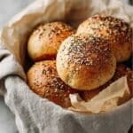 Keto bread buns topped with everything bagel seasoning in a parchment-lined basket