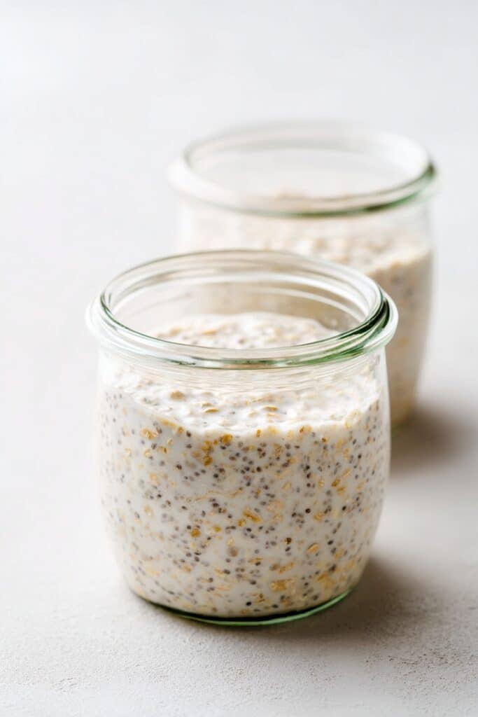 Keto Overnight Oats That Actually Taste Like the Real Thing - 2025 3 Two small glass jars filled with plain keto overnight oats made with chia seeds and cream on a neutral surface