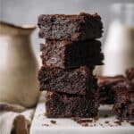 A stack of rich vegan protein brownies on marble with soft background.