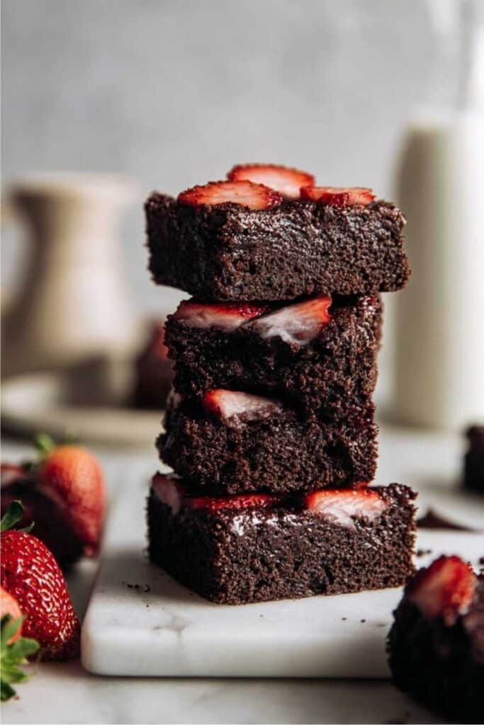 Vegan Protein Brownies – A Rich, Guilt-Free Treat You’ll Crave 1 Stack of vegan protein brownies with sliced strawberries on top.