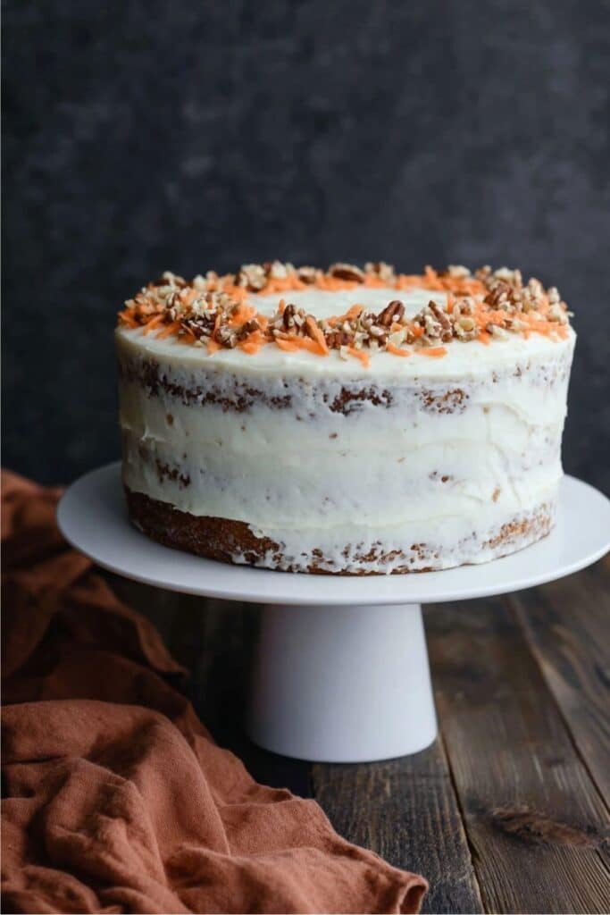 Keto Carrot Cake Recipe That’s Moist, Easy & Perfect for Low Carb Days 1 Whole keto carrot cake with cream cheese frosting and pecan-carrot topping on cake stand